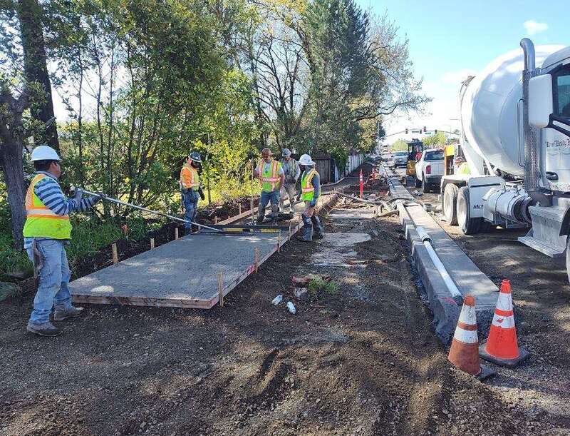 Pouring concrete and finishing the surface of a new sidewalk